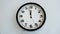 Closeup of White Clock Face on white wall clock, arrows show 12:00 or 00:00