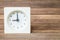 Closeup white clock showed nine o `clock on blurred brown wood board background