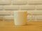 Closeup White Cofee Cup on the wooden table with White Brick wall background.