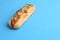 Closeup of a whole delicious hot dog with melted cheese and pepper isolated on a blue background