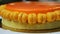 Closeup whole round orange glazed cake with mini macaroons rotates around