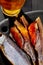 Closeup of whole and skinned salted air-dried roach with roe served with beer on black background