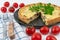 Closeup wide studio shot of freshly baked yellow French salty cake, or quiche with mushrooms, red cherry tomatoes, green mint and