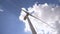 Closeup of windmills against blue sky and white clouds