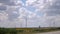 Closeup of windmills against blue sky and white clouds