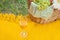 Closeup of wine glasse on the yellow cover, picnic basket with food and flower on the green grass