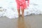 Closeup of a woman bare feet standing at sandy beach, with a wave foaming - travel and relaxing. Female leg walking on the beach.