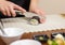 Closeup of woman chef cutting japanese sushi roll