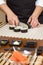 Closeup of woman chef cutting japanese sushi roll