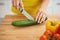 Closeup on woman cutting cucumber on cutting board