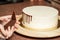 Closeup of a woman decorating white smooth cake's edges with chocolate in a pipe bag, in the kitchen