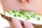 Closeup of an woman, eating a sandwich or bread with fresh, healthy microgreens