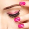 Closeup woman face with pink nails near eyes.