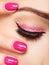 Closeup woman face with pink nails near eyes.