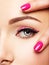 Closeup woman face with pink nails near eyes.