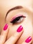 Closeup woman face with pink nails near eyes.