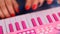 Closeup woman fingers press keys on pink piano