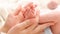 Closeup of woman gently stroking with hand tiny feet of her newborn baby son with perfect skin. Concept of family