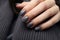 Closeup woman hand with dark gray and black nail polish on fingernails. Nail manicure with gel polish at luxury beauty salon.