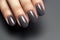 Closeup woman hand with dark gray and black nail polish on fingernails. Nail manicure with gel polish at luxury beauty salon.