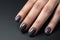 Closeup woman hand with dark gray and black nail polish on fingernails. Nail manicure with gel polish at luxury beauty salon.