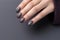 Closeup woman hand with dark gray and black nail polish on fingernails. Nail manicure with gel polish at luxury beauty salon.