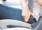 Closeup woman hand sitting inside car fastening seat belt.