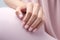 Closeup woman hand with soft pink nail polish on fingernails. Soft pink nail manicure with gel polish at luxury beauty salon.