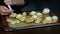 Closeup woman hands fill custard cookies choux by pastry bag with white cream