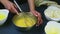 Closeup woman hands leave metal whisk in mixed egg yolks with sugar in small bowl