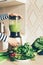 Closeup woman hands making green smoothie in blender bowl