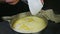 Closeup woman hands pour whipped cream into metal bowl with yeast dough