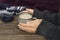 Closeup of woman hands who holding a cup of hot chocolate, knitted scarf and mittens on the wooden rustic table