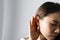 Closeup of Woman holds her hand near ear and listens carefully on grey background. Hearing problem  deaf concept