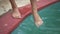 Closeup of woman legs standing on edge of swimming pool and putting feet into water