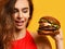 Closeup woman look at big barbecue burger sandwich with hungry mouth happy smiling on yellow background