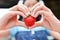 Closeup on woman making heart with strawberry.Young adult woman holds in hand fresh sweet strawberry in heart shape