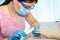 Closeup woman in a nail salon receiving a manicure by a beautician with nail file. Beautician file nails to customer