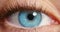 Closeup of a woman opening her blue eye with her pupils dilating with beautiful long eyelashes. Macro zoom of a girl