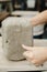 Closeup of woman potter cutting clay with wire cutter in ceramic studio