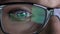 Closeup woman\'s eye in glasses works on laptop at night