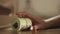 Closeup of a woman`s hand hides a stack of dollar bills under the bed