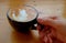 Closeup of woman`s hand holding a cup of cappuccino coffee on wooden table