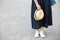 Closeup of woman`s hand holding nice straw hat. Woman in long dress and white sneakers with a hat in her hand