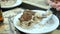 Closeup of a woman`s hand with spoon eating a piece off a homemade cake with chocolate chips.