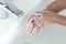 Closeup woman`s hand washing with soap in bathroom, selective focus