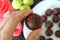 Closeup of woman`s hand whith healthy sweet treats. Cooking chocolate energy balls with almonds.