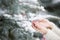 Closeup of woman`s hands decorating Christmas tree with crystal star decor outdoors. Traditional celebration