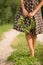 Closeup of woman`s hands holding floral wreath. Woman in dotted dress holding wild flowers wreath and standing on a road