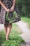 Closeup of woman\'s hands holding floral wreath. Woman in dotted dress holding wild flowers wreath and standing on a road